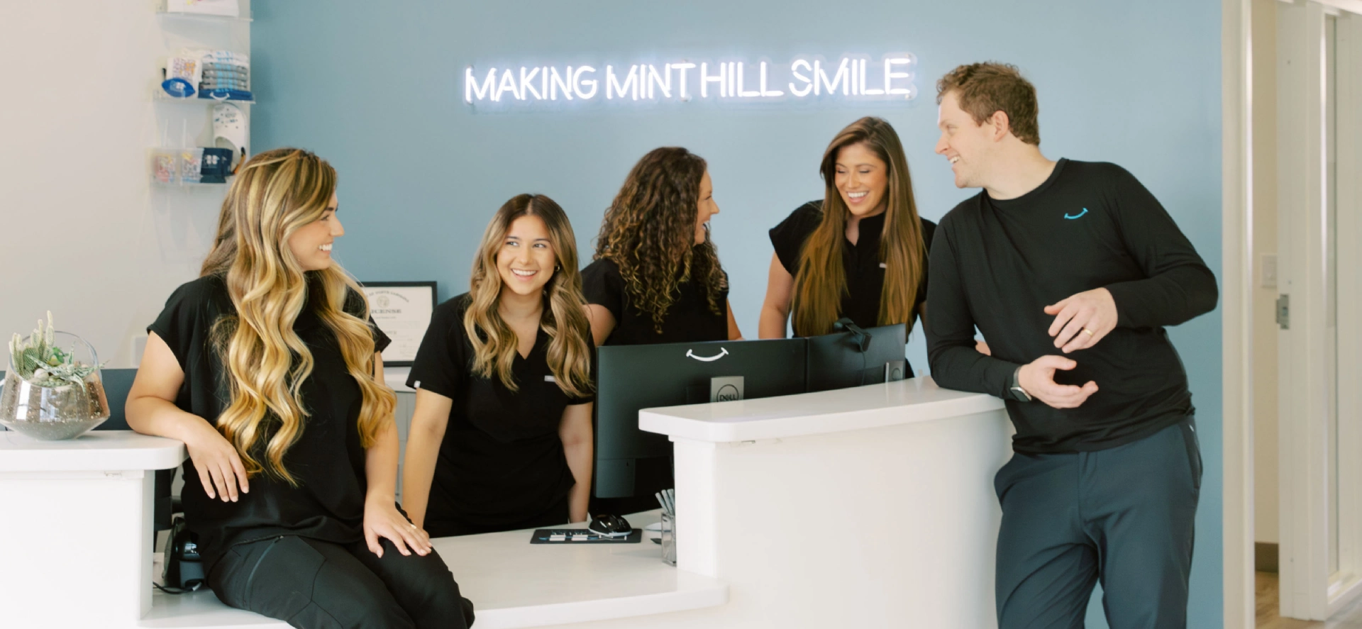 The orthodontic team smiling and laughing around the front desk