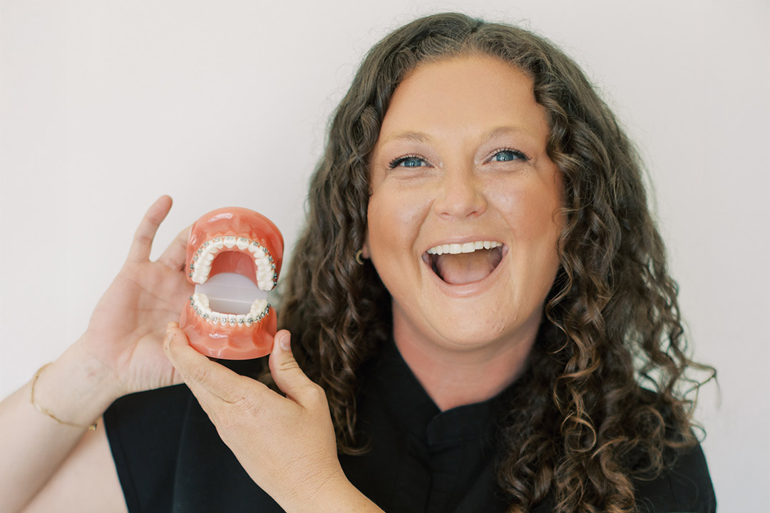 Woman smiling holding up a teeth model