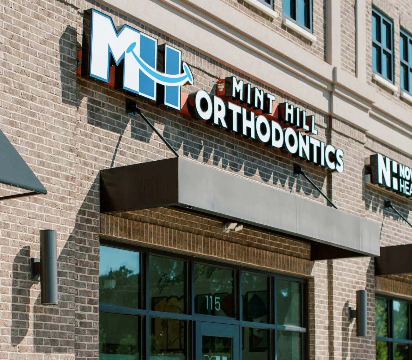 Exterior storefront of Mint Hill Orthodontics with brick facade and blue logo signage