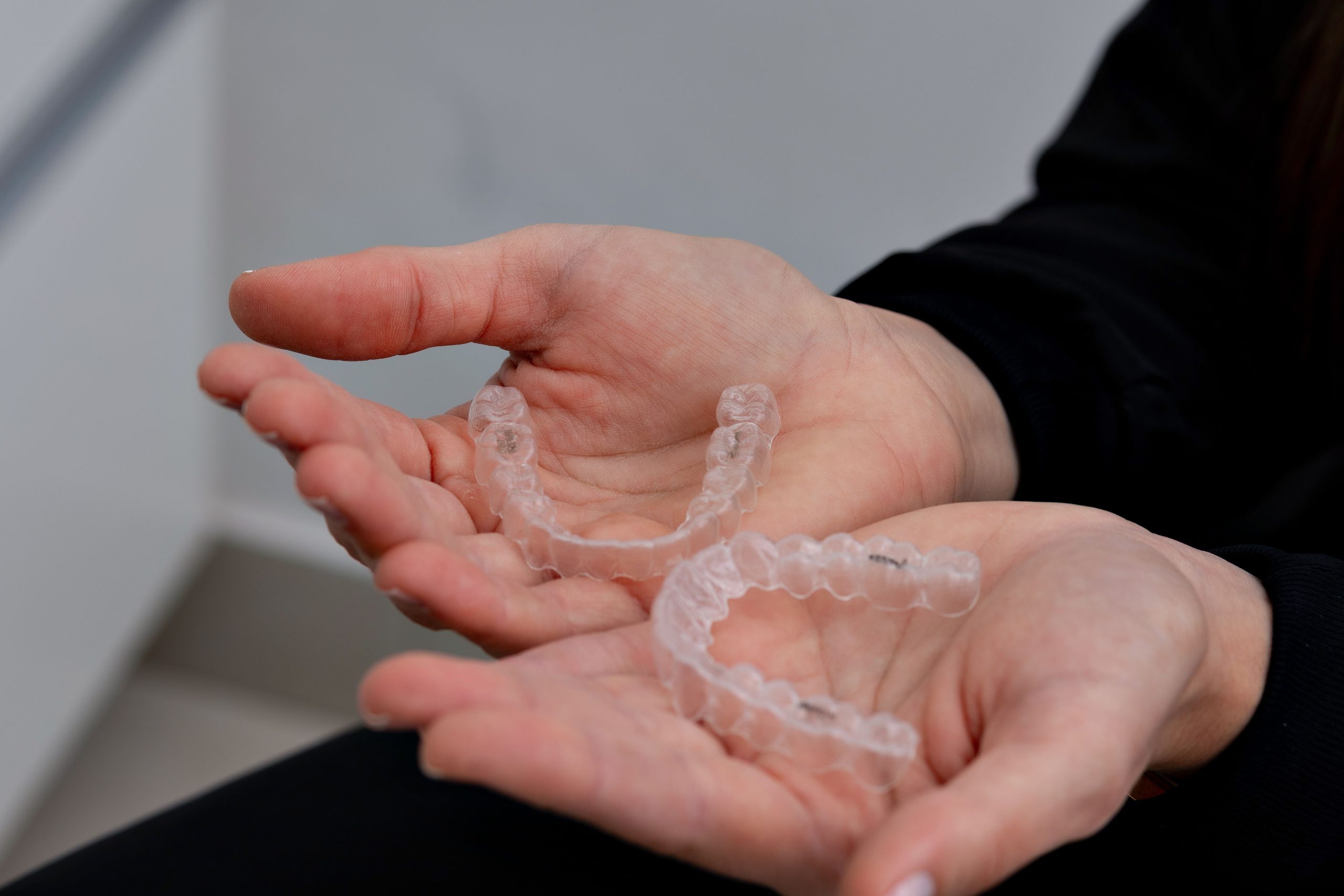 A person holding two Invisaligns in their two palms